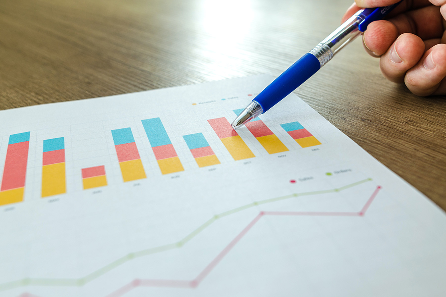 Person using pen to point at graphs printed on page