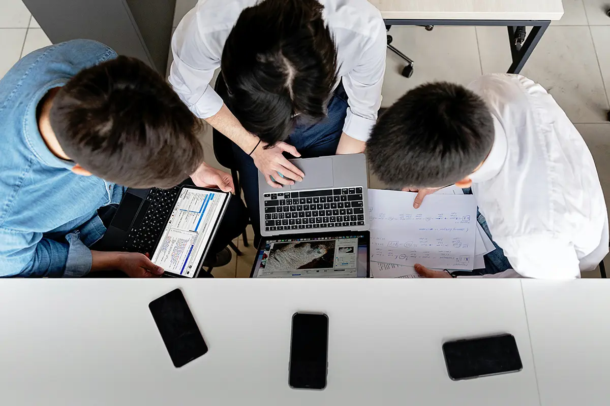 WAN_3 group of colleagues gathered around laptop