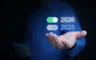Person in blue shirt holding a smartphone and presenting a digital overlay with toggle switches for years 2025 and 2026, symbolizing future planning and technological transition.